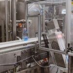 Moderne verpakkingslijn met geautomatiseerde vulmachines en traysealers in een voedselindustrieomgeving.